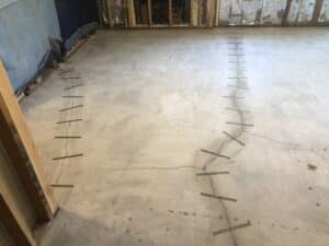 The same cracked concrete floor now reinforced with multiple Crack Stitch carbon fiber staples installed in a staggered pattern across the length of the crack.