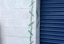 The outside of a storage unit showing a crack in the concrete wall that was filled with epoxy and stitching.