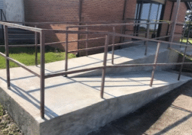 Concrete ramp leading to the front door of a building, providing accessible entry for individuals with mobility challenges